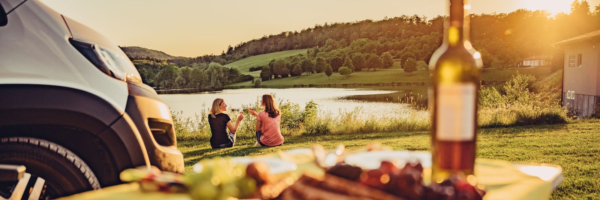Camper genießen den Sonnenuntergang am See mit einem Glas Wein | HeilbronnerLand | Wohnmobiltouren in Baden-Württemberg